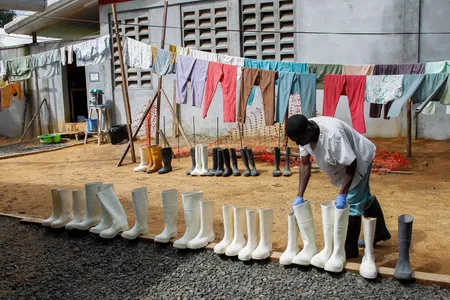 A nurse at the ELWA Ebola Treatment Unit in Monrovia, Liberia, picks up disinfected boots