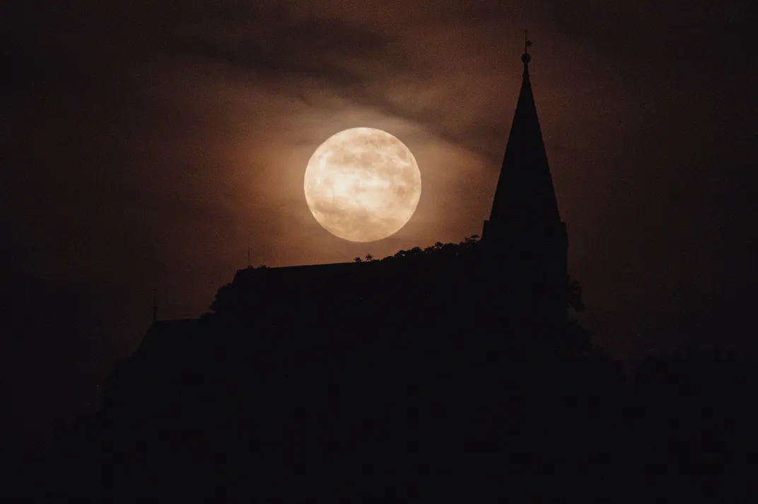Strawberry moon rises above a Reformed Church in Abaujvar, Hungary,