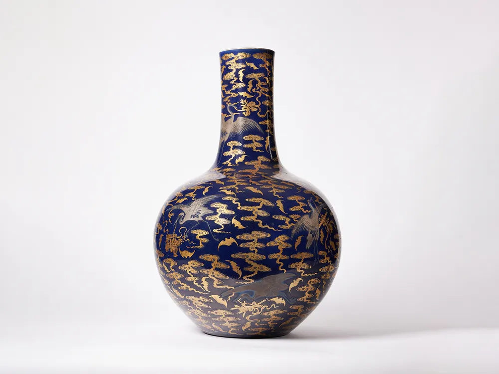 Picture of a blue and gold vase with a round body and thin neck