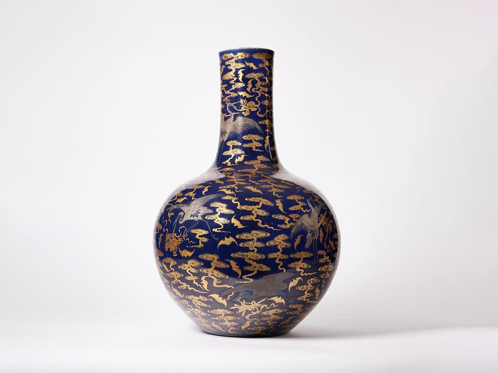 Picture of a blue and gold vase with a round body and thin neck