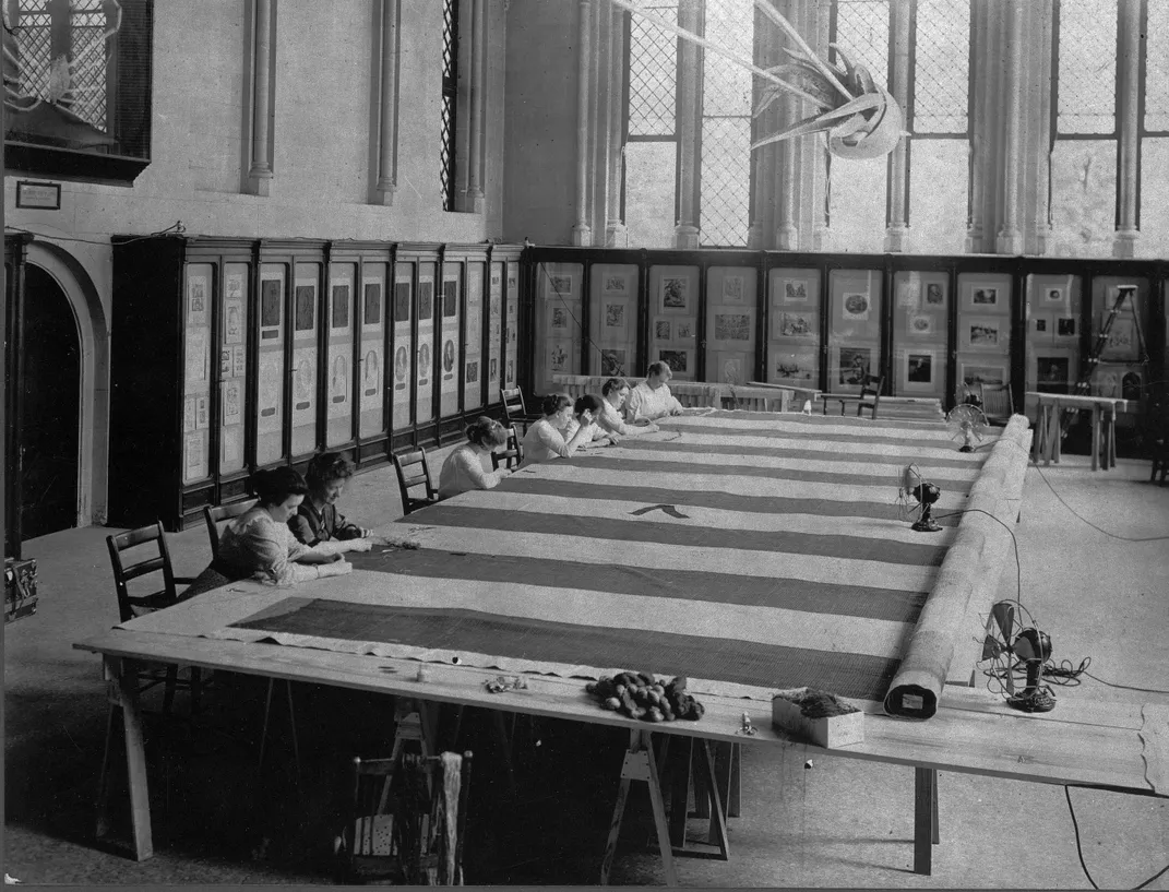 Women at work repairing the Star-Spangled Banner on a set of makeshift tables in the Smithsonian Castle in 1914