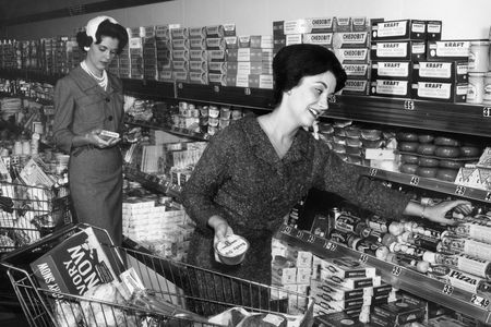 A woman smiles as she reaches for a container of Betty Crocker pizza dough mix, in the dairy section of a grocery store.