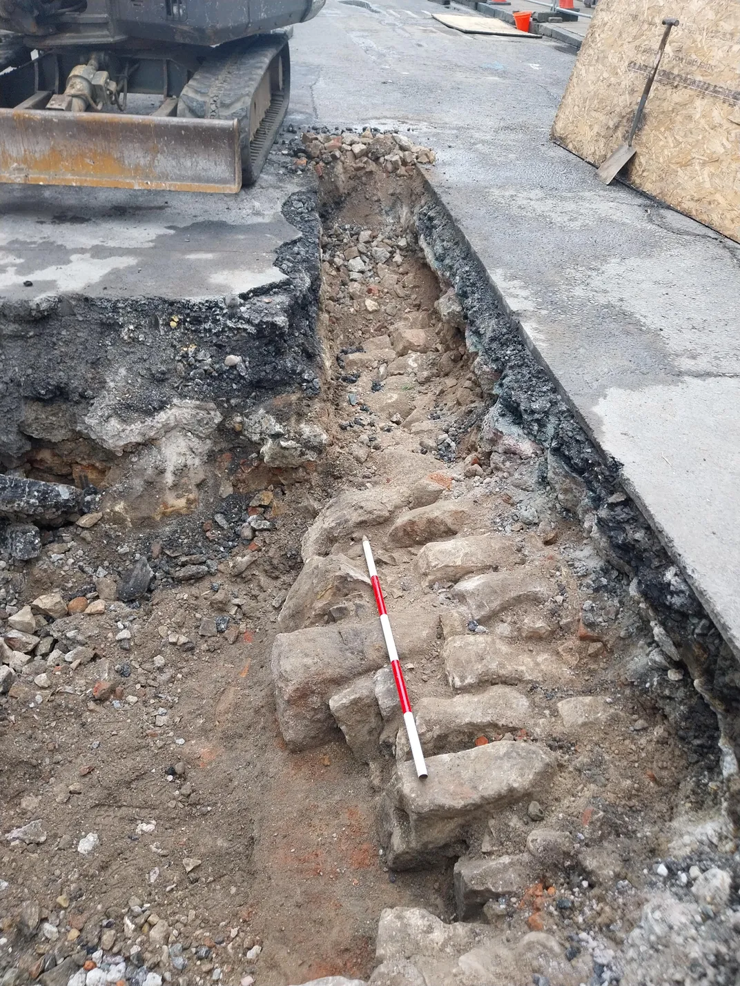 Old bricks protruding from hole under roadway