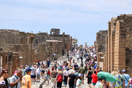 A crowd of tourists gathers on the main street at Pompeii.