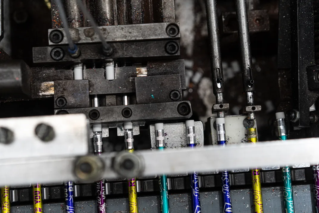 a machine puts erasers onto pencils