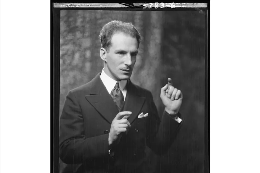 A black and white photograph of Theremin from the waist up, holding one hand up and his other to the side as though he is playing his namesake instrument