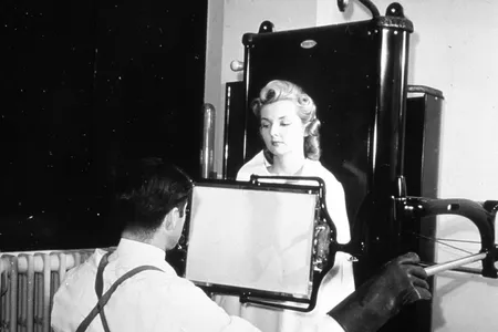 A technician takes an X-ray fluoroscope of a female patient. Fluoroscope exams delivered much more radiation exposures than modern X-rays.
