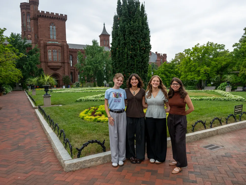 Four interns stand for a picture in front of the Smithsonian Castle’s garden entrance.