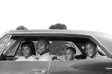 1960s family sitting in four-door sedan automobile