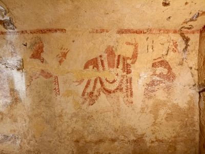The left wall features a painting of men and women dancing around a flute player.