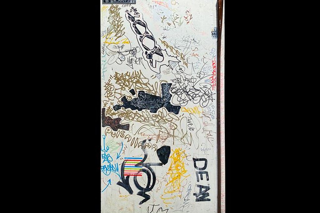 A white refrigerator door covered in scribbles, multicolored graffiti tags, signatures, cartoons, and more