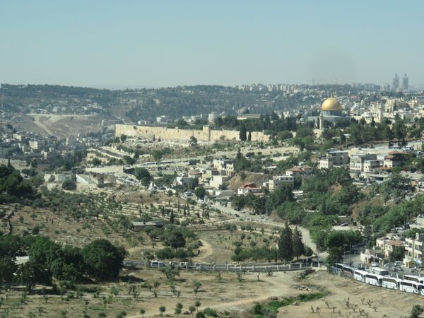 The golden Dome of the Rock mosque sits beyond the Old City walls, with the modern City of David and ancient Mount of Olives in the foreground. thumbnail