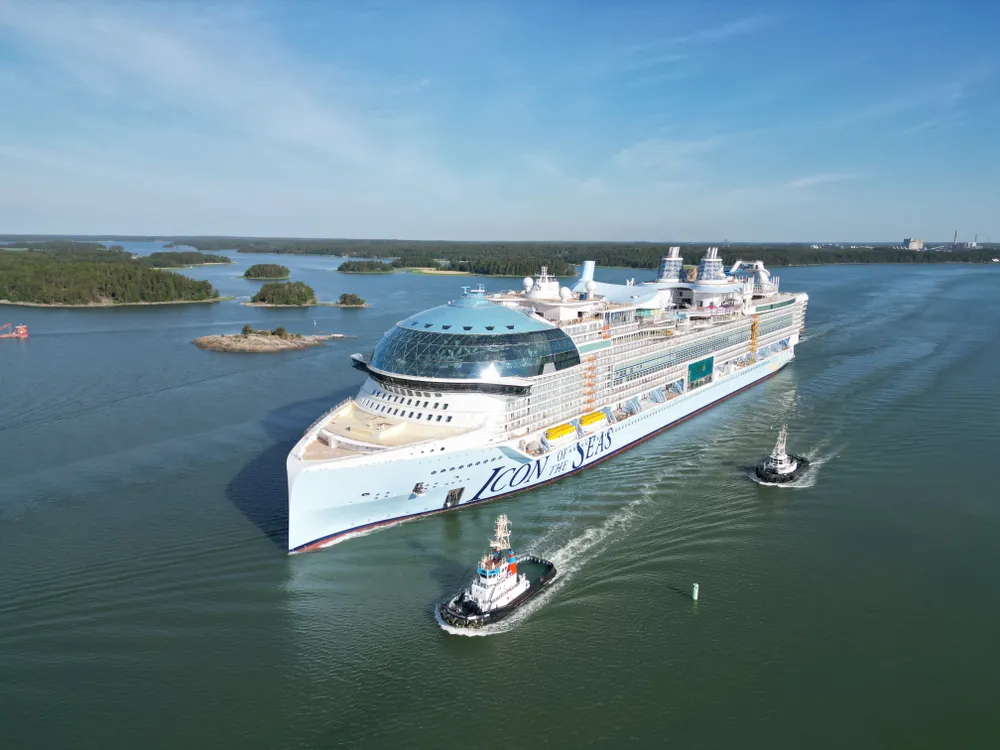 Large cruise ship with tug boats in the water nearby