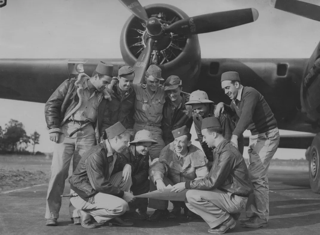 A 100th bomber crew plans a route under the engines of its B-17 Flying Fortress. Egan is crouching, second from right.