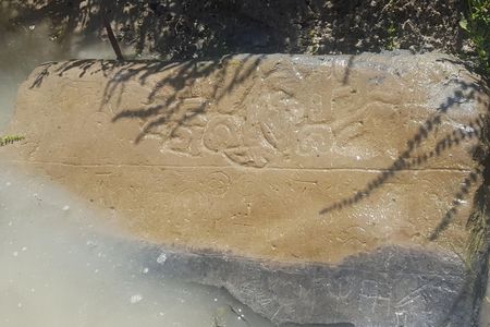 A half-submerged stone inscribed with Luwian hieroglyphs detailing the fall of Phrygia