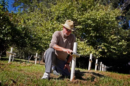 Roger Kiser, a member of the 'White House Boys', kneels in front of a cross while visiting the small graveyard at the former Florida School for Boys in Marianna, Florida, on October 29, 2008.