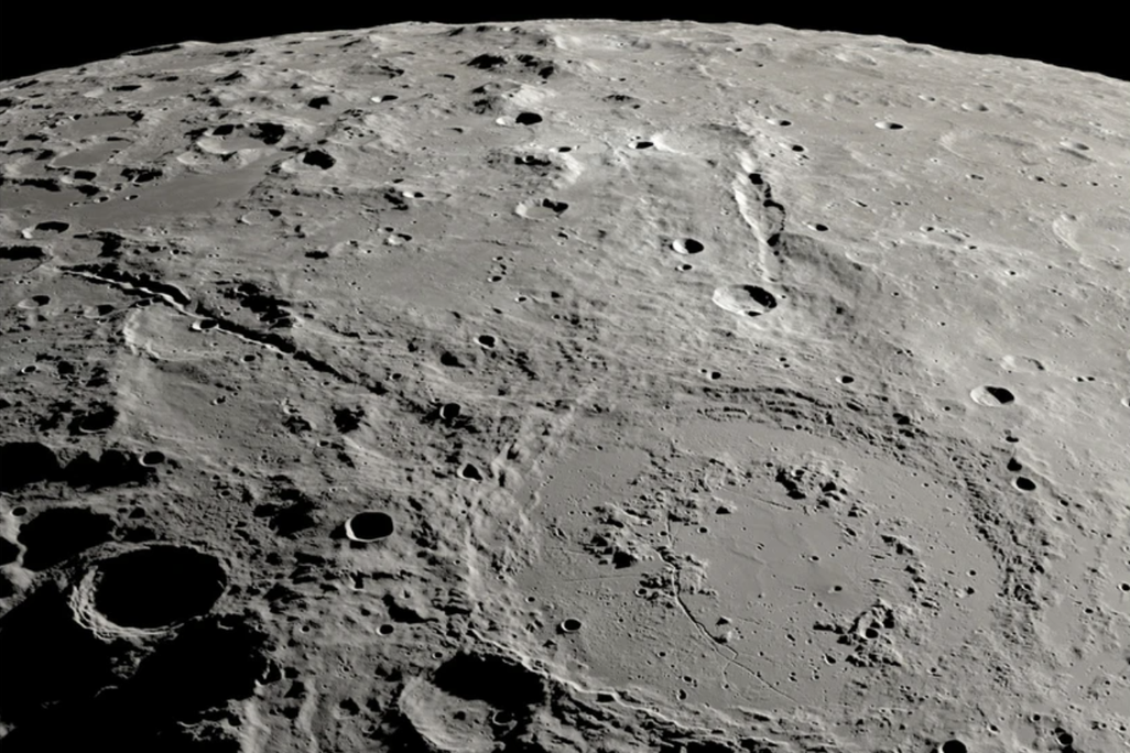an overhead view of a large crater on the moon with two canyon lines stretching out from it