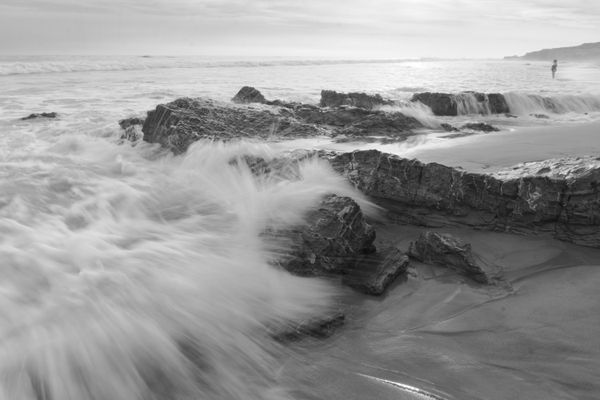A wave crashes over rocks at Crystal Cove State Park. thumbnail