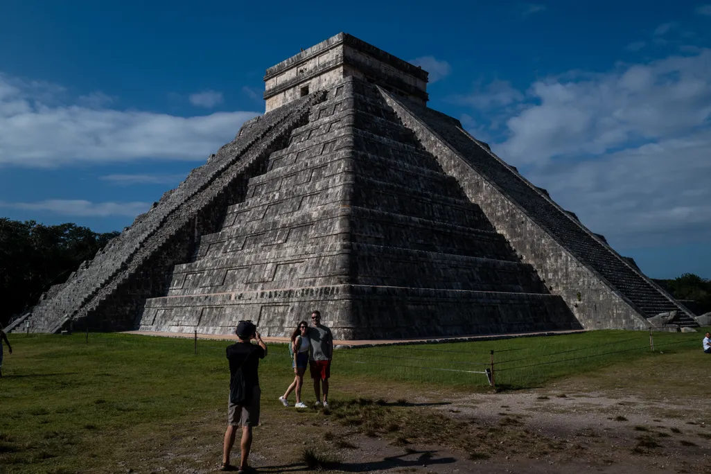 Man and woman posing for photo in front of pyramid-like structure