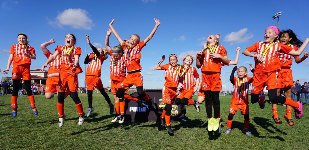 a soccer team jumps for joy after receiving medals