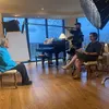 Barbara Franklin seated in the center of a room surrounded by lighting and sound equipment. Rachel Seidman sits facing her approximate five feet away with papers in her lap.