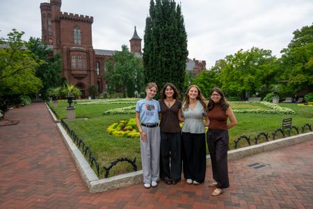 Four interns stand for a picture in front of the Smithsonian Castle’s garden entrance.