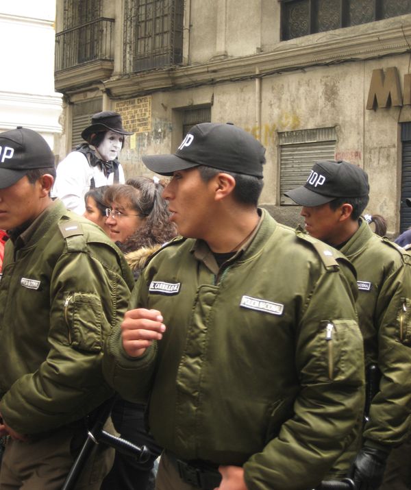 Bolivian troops cross before a street performing mime. thumbnail