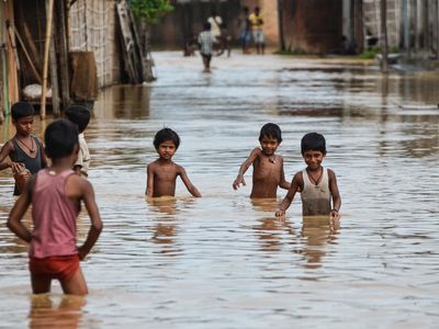 Children wade through flood waters in northern India in July 2013. 
