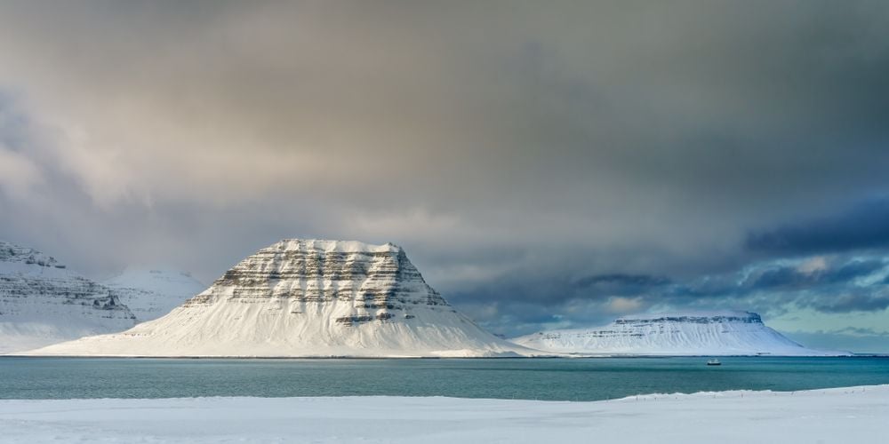 I captured this image on a cold morning in February, 2022 in the Snaefellsnes Peninsula area of Iceland.  It had snowed the night before and as I came around a corner in the road heading toward Kirkjufell and the town of Grundarfjörður, I saw a fishing trawler heading out to sea.  The last rays of sunlight were striking Kirkjufell and a storm was moving in, but the fishing trawler was heading out for the day regardless.  The trawler also provides scale so that the viewer can comprehend the size and scope of Kirkjufell and the surrounding mountains.  This is a rugged, but remarkably beautiful part of Iceland that I love visiting and photographing in the winter.