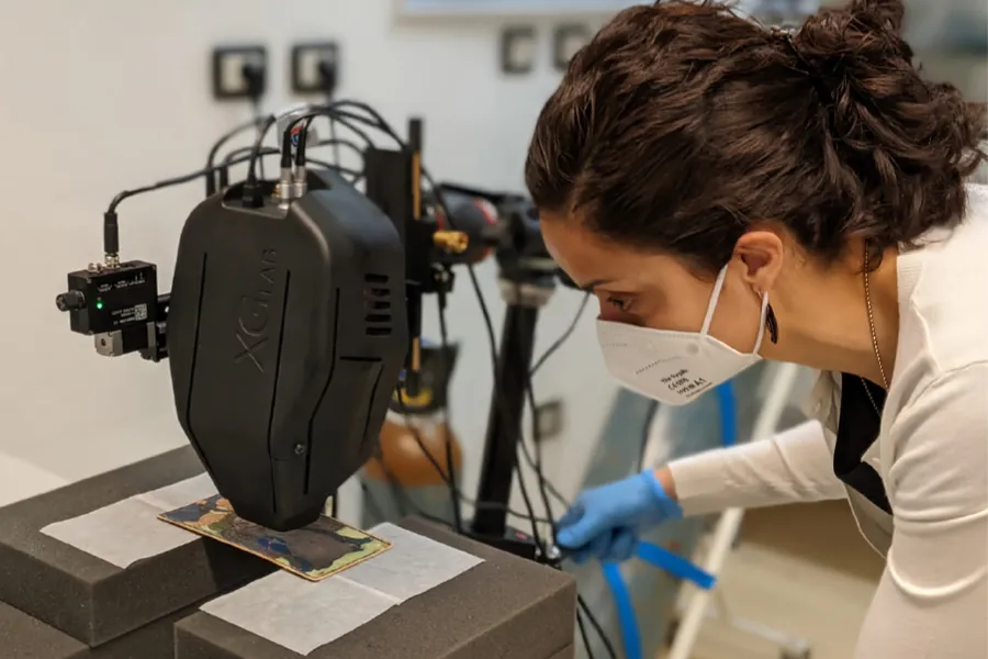 a researcher uses a portatble X-ray fluorescence spectrometer to look at a tarot card