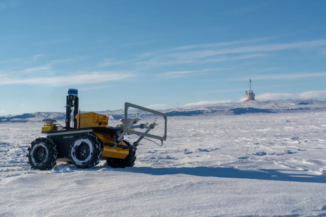 An image of a yellow robot standing idle in a snowy terrain