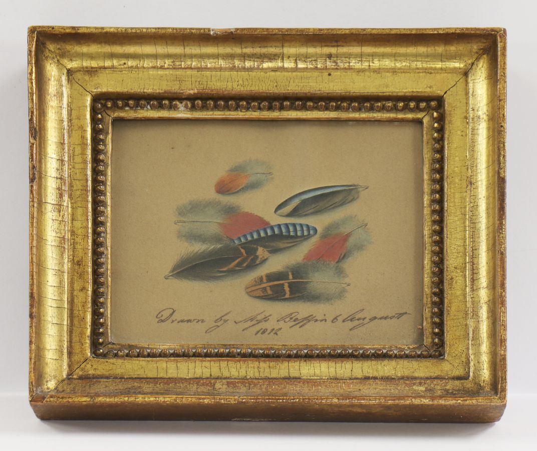 A gilt-framed miniature drawing of a pile of feathers with an elegant ink inscription
