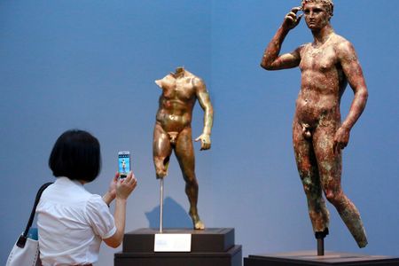 A reporter photographs "Statue of a Victorious Youth" on display at the J. Paul Getty Museum.