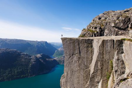 A man stands on Preikestolen (Pulpit Rock) above Lysefjord.