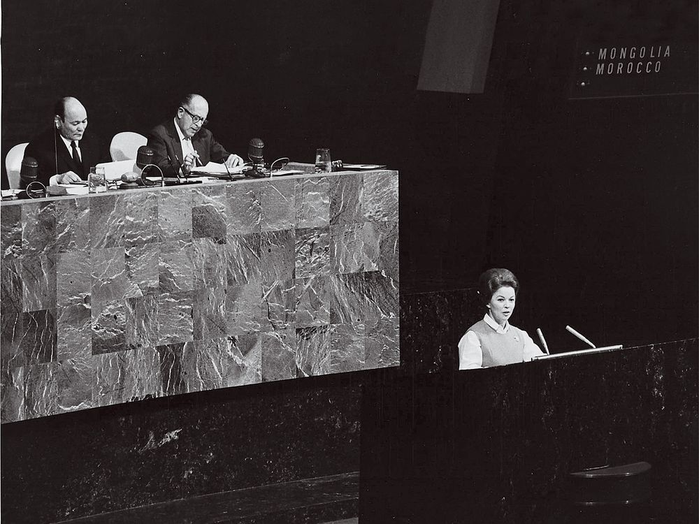 a black and white photo of Shirley Temple Black speaking at a microphone