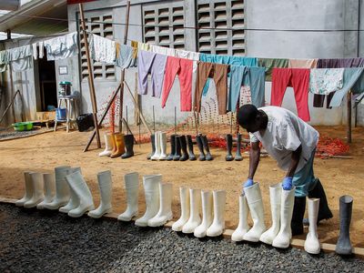 A nurse at the ELWA Ebola Treatment Unit in Monrovia, Liberia, picks up disinfected boots