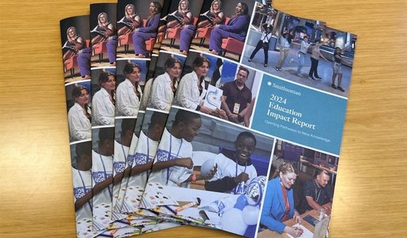 Seven copies of the Impact Report are fanned out on a wood table.