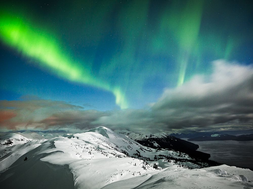 The Northern Lights Blast Over A Moon Lit Ridge In Juneau Ak