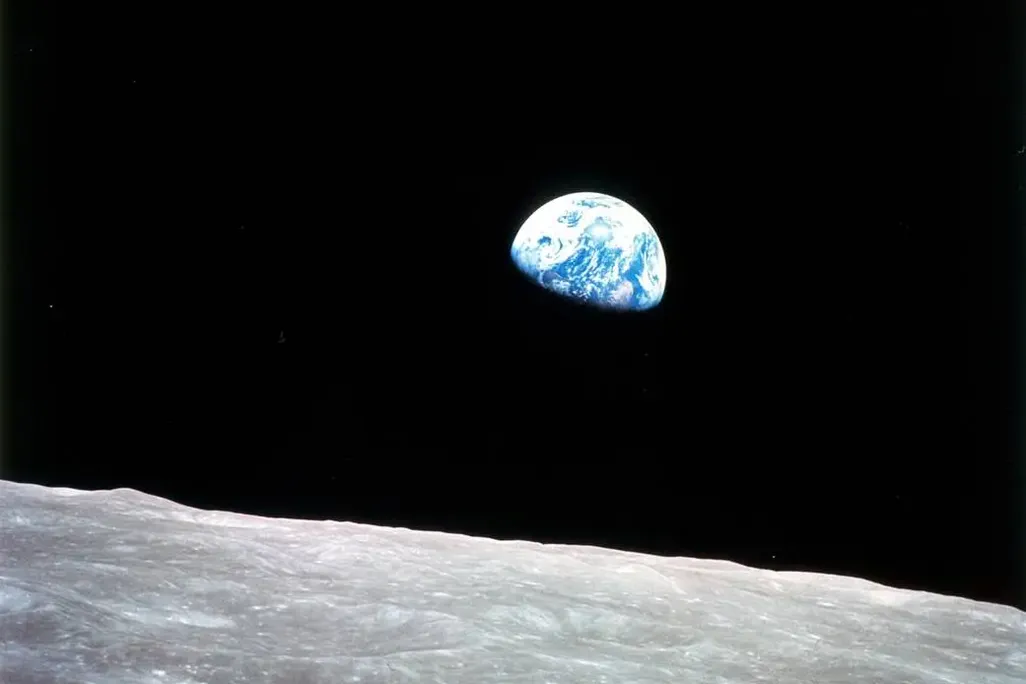 Earth emerges over the moon's horizon.