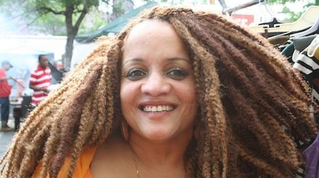 A priestess of Osun in the Yoruba tradition shops at the Dance Africa Festival and Bazaar in New York City. Her natural hair is combined with synthetics to produce her style.