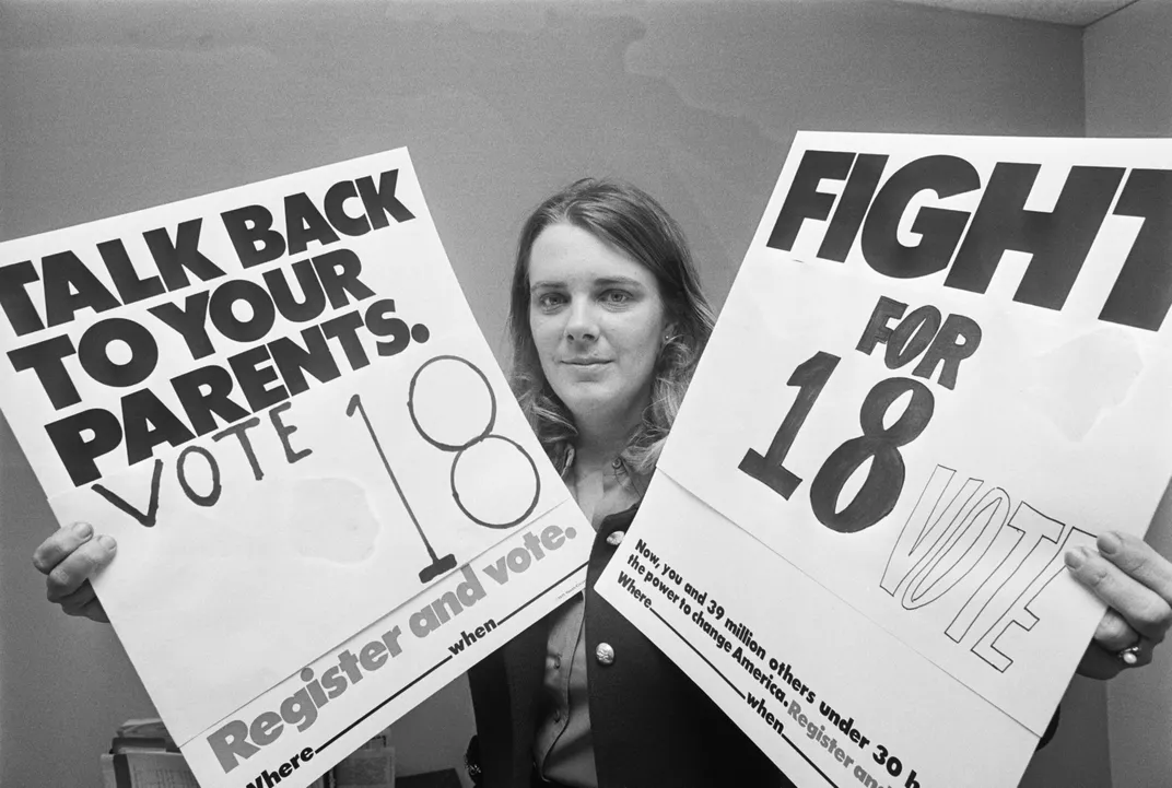 Woman holding signs that say Talk Back to Your Parents. Vote 18 and Fight for 18