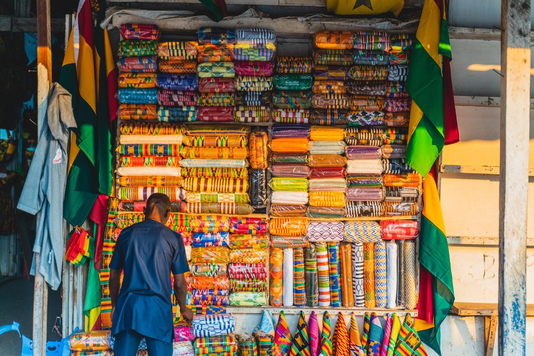 A merchant tends to his stacks of kente cloth at a market in Ghana