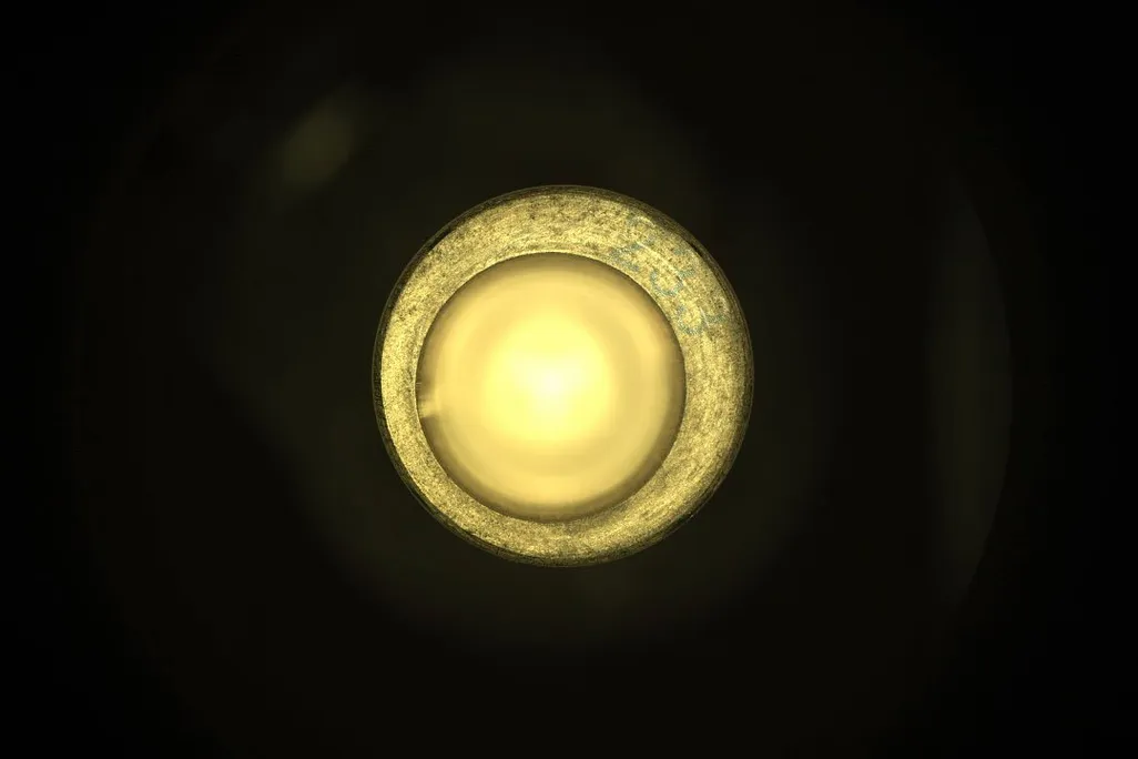 An image of the inside one of the Mars Rover's sample tubes. In the image the tube looks like a small yellow circle. The tube is empty.