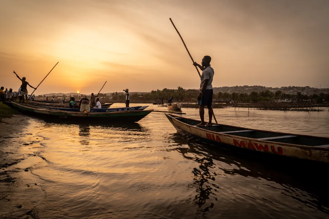 African fishermen stand atop boats at sunrise