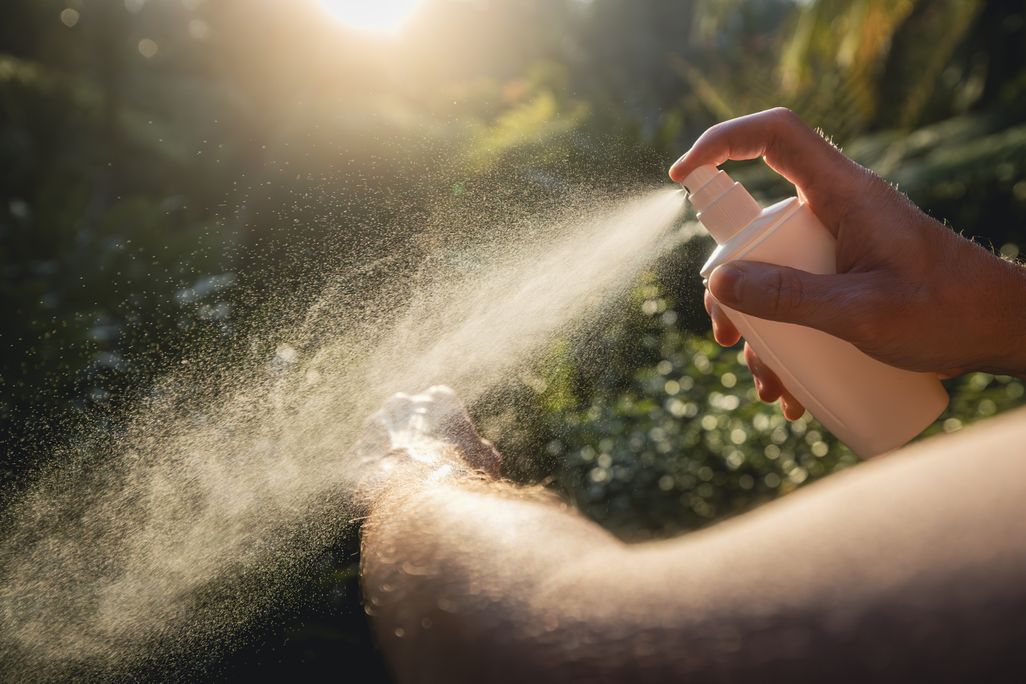 A person spraying their am with bug spray