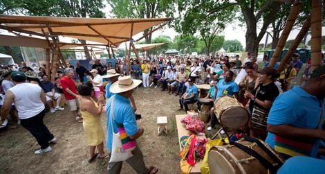 Visitors and artists interact under the guadua (bamboo) tents in the Colombia program area.