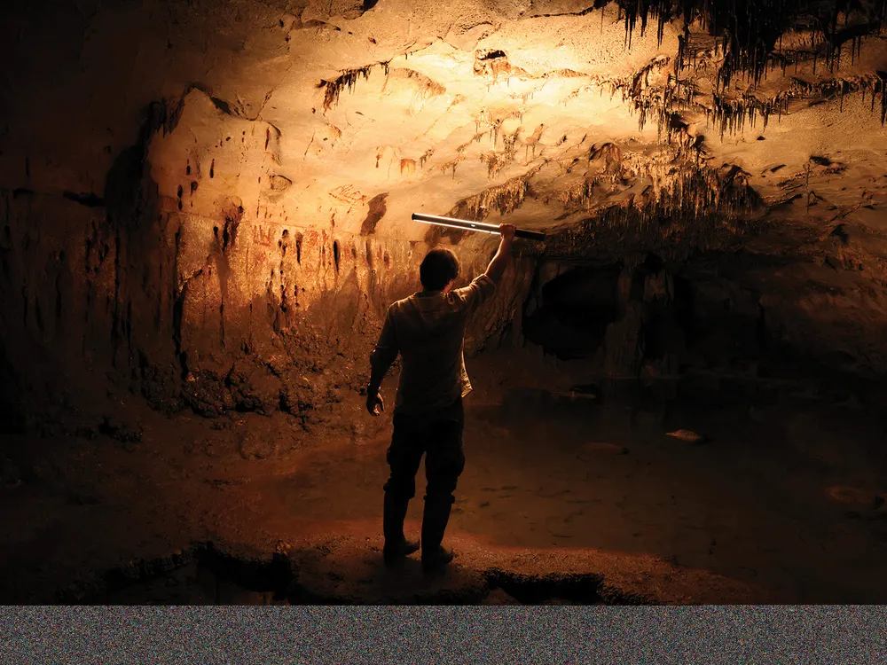 a man holding a flashlight inside a cave