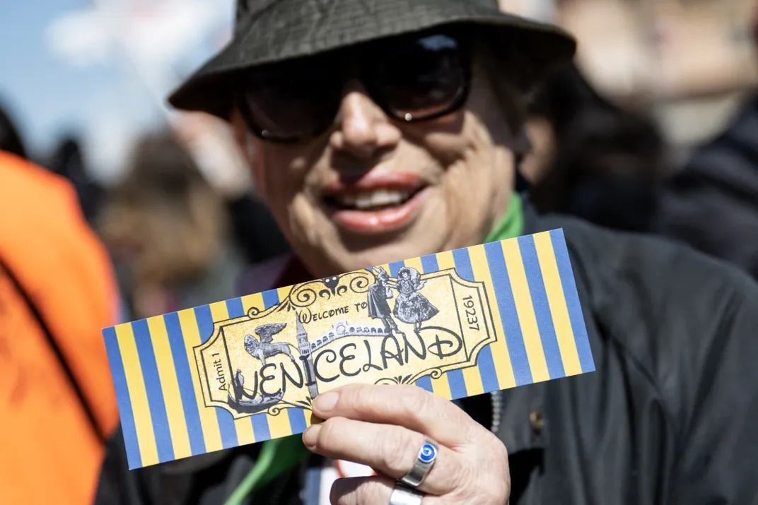 A woman holds a ticket reading "Welcome to Veniceland" as protesters take part in a demonstration against the new tax on April 25.