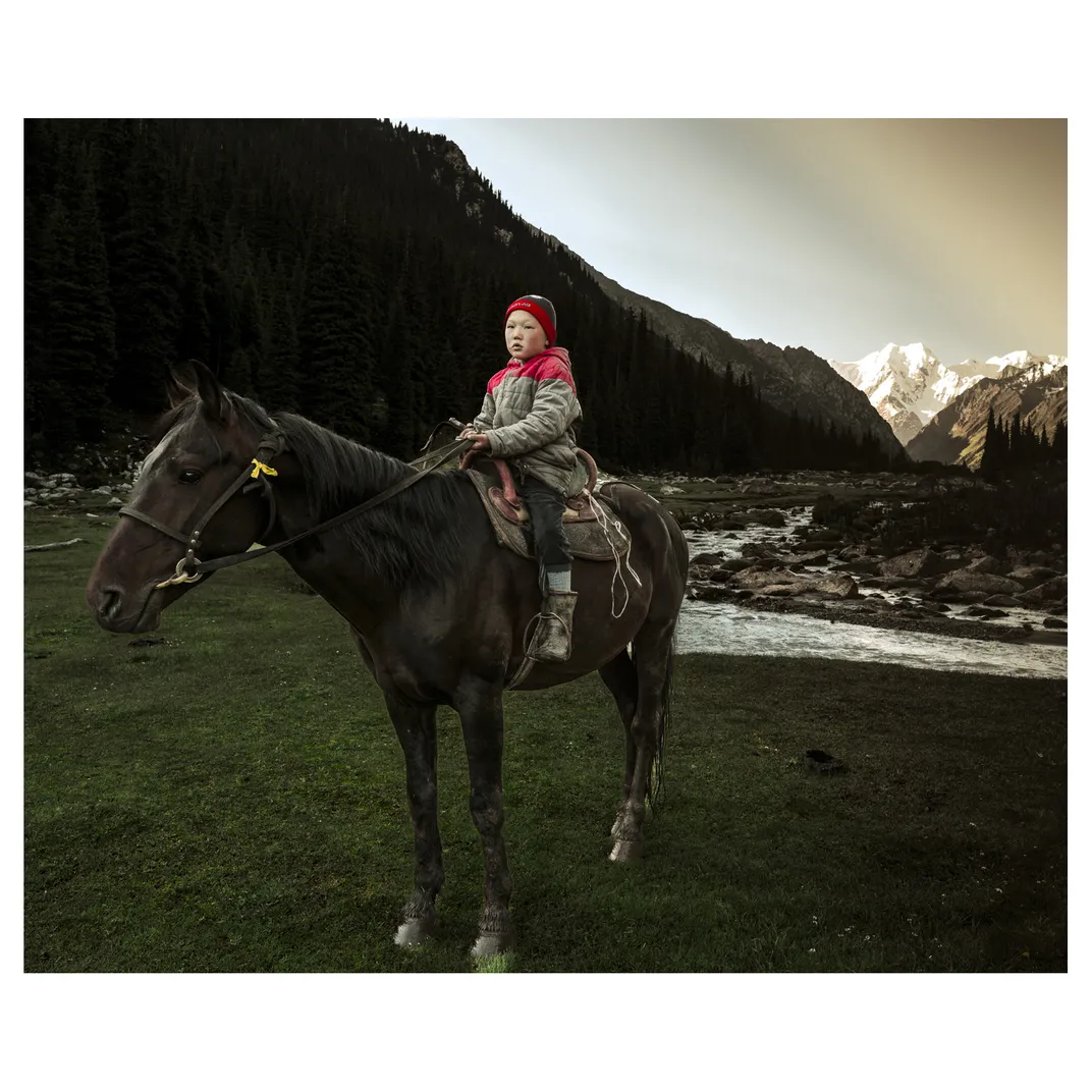 a child sits on a horse with mountains behind them