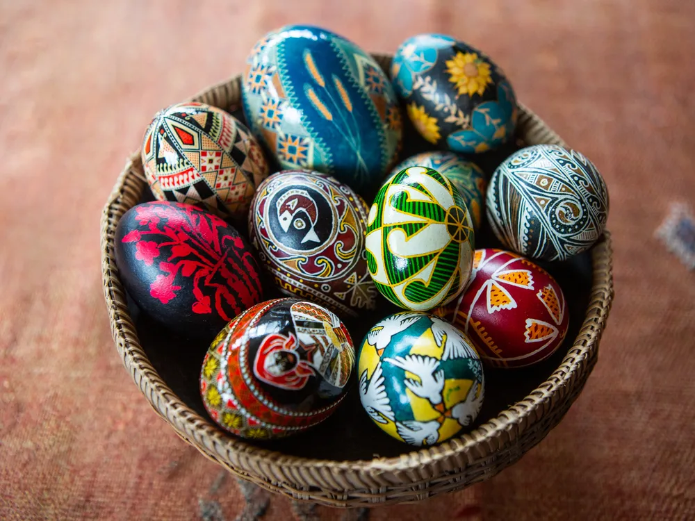 A bowl filled with intricately decorated, multicolored eggs